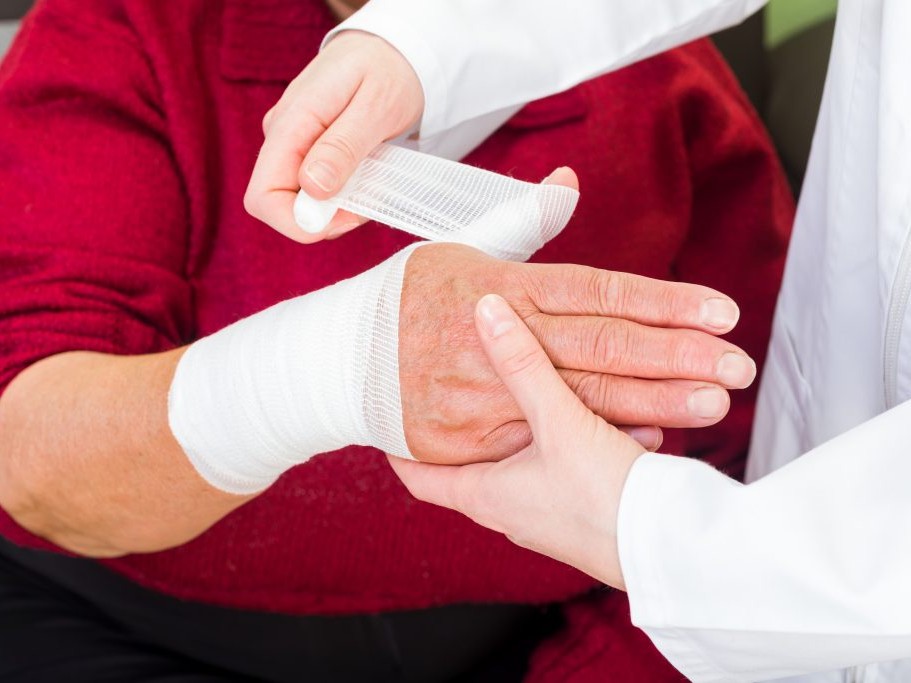 Healthcare professional treating a wound with sterile dressings and medical supplies.